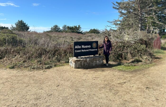 woman standing next to ano nuevo sign